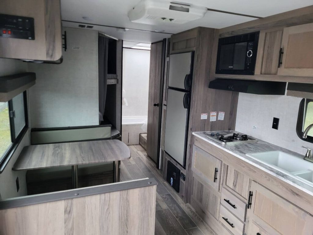 Gulf Stream Trailmaster dining and kitchen area, with bathroom view in the back