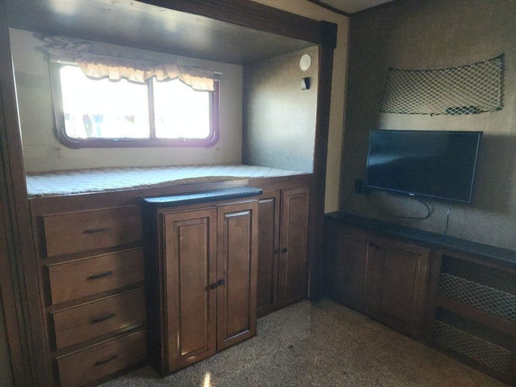 An additional bed, storage space, and tv inside the 2015 Heartland Gateway