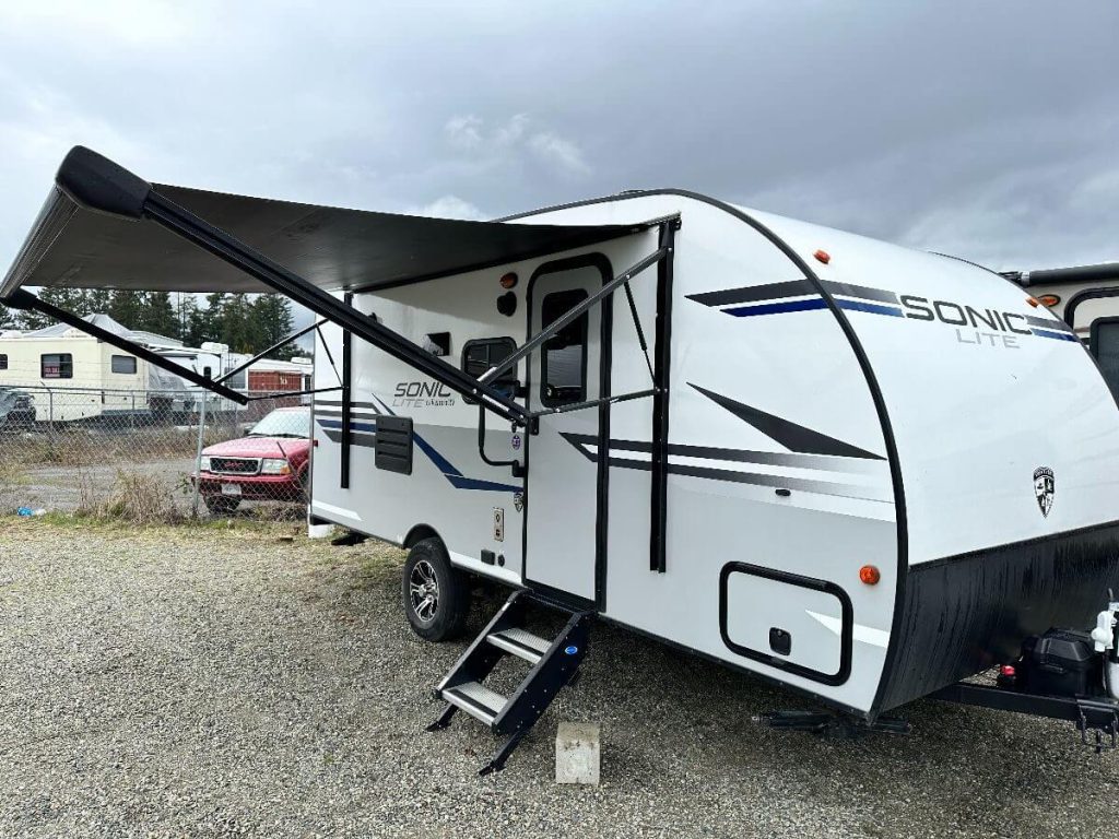 Exterior side view of RV with awning pulled out.