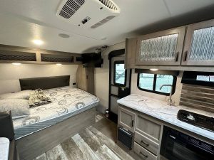 Interior of Sonic RV showing bed, door, and kitchenette