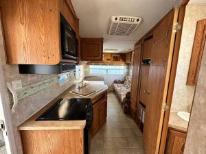 Full length interior view showing glimpse of bathroom, kitchen, eating area, and seating area.